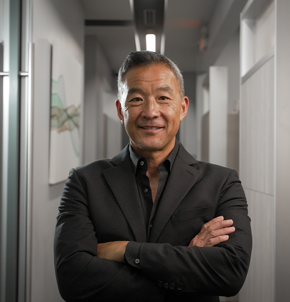 Dr. Chin smiling with his arms folded in the office