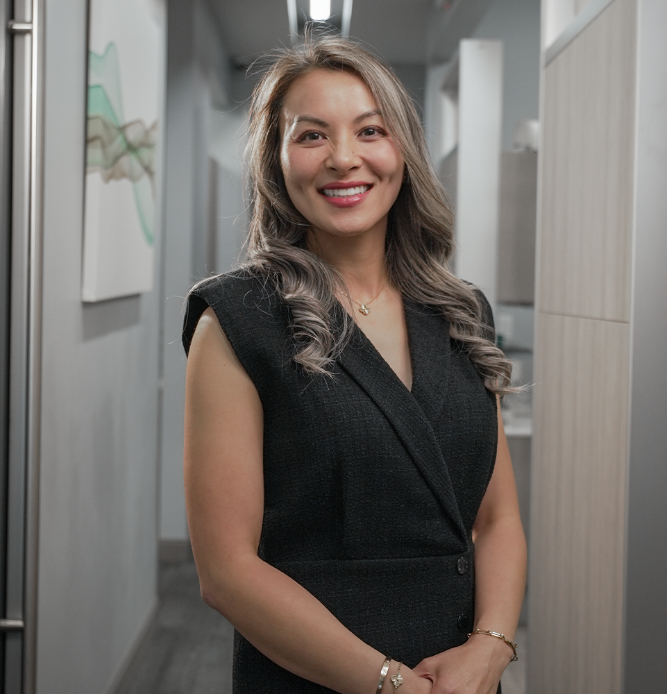 Dr. Dingh smiling in the office with her hands crossed around her waste
