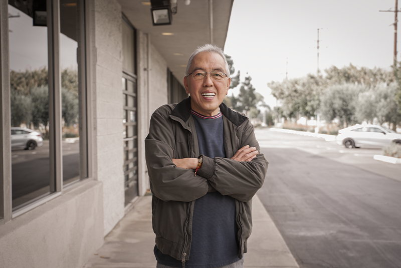male patient standing outside the office and smiling with arms folded