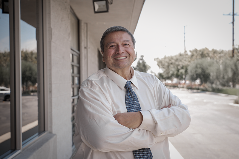 male patient standing outside the office and smiling with arms folded