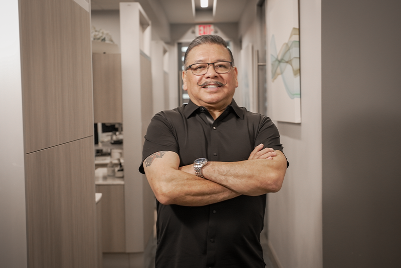 male patient standing in the office with arms folded and smiling