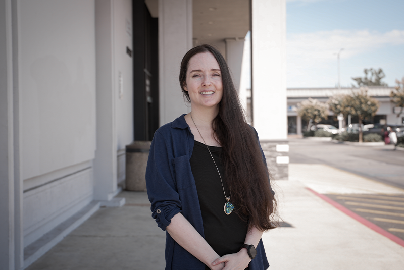 female patient standing outside the office and smiling with her hands crossed around her waste