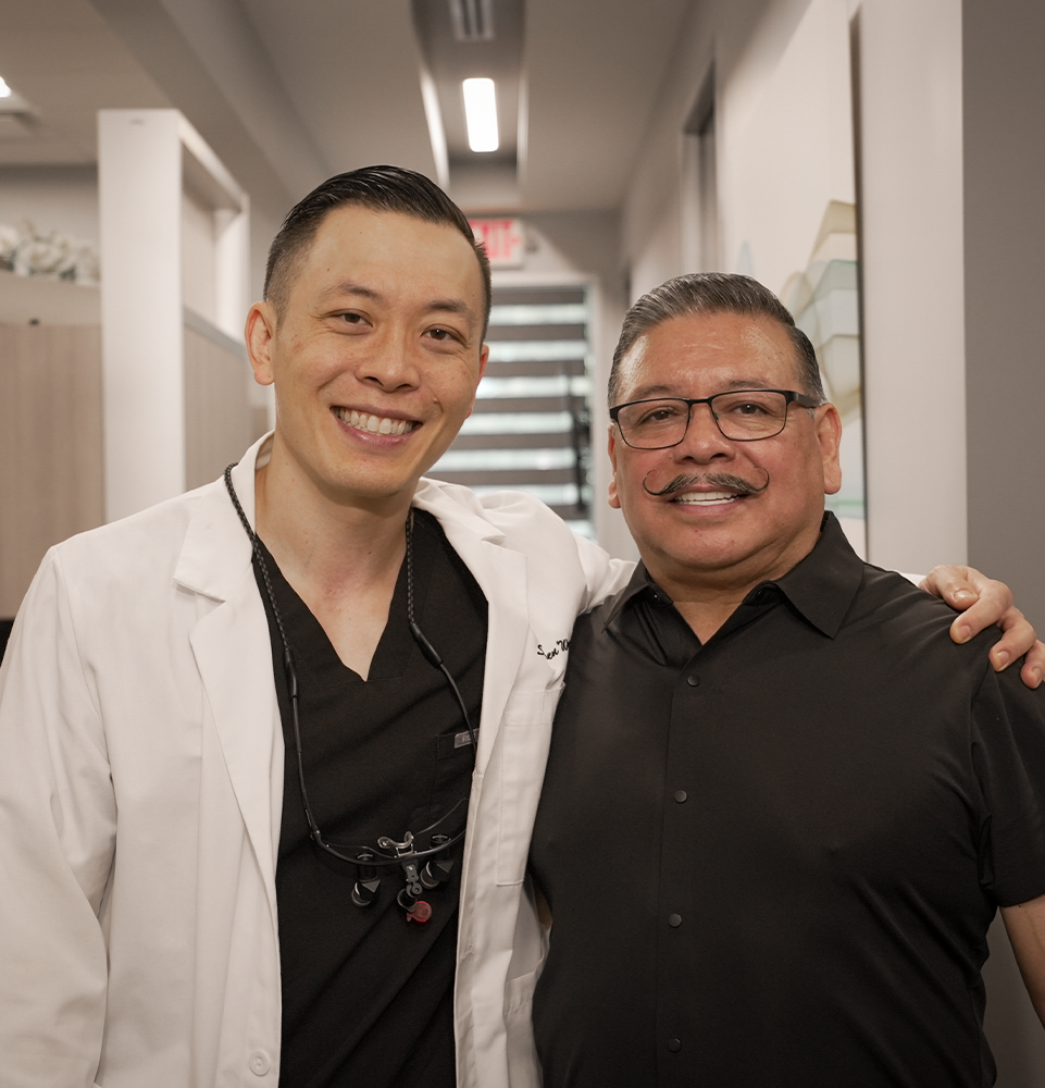 Dr Wong with his patient Jose standing inside the office smiling